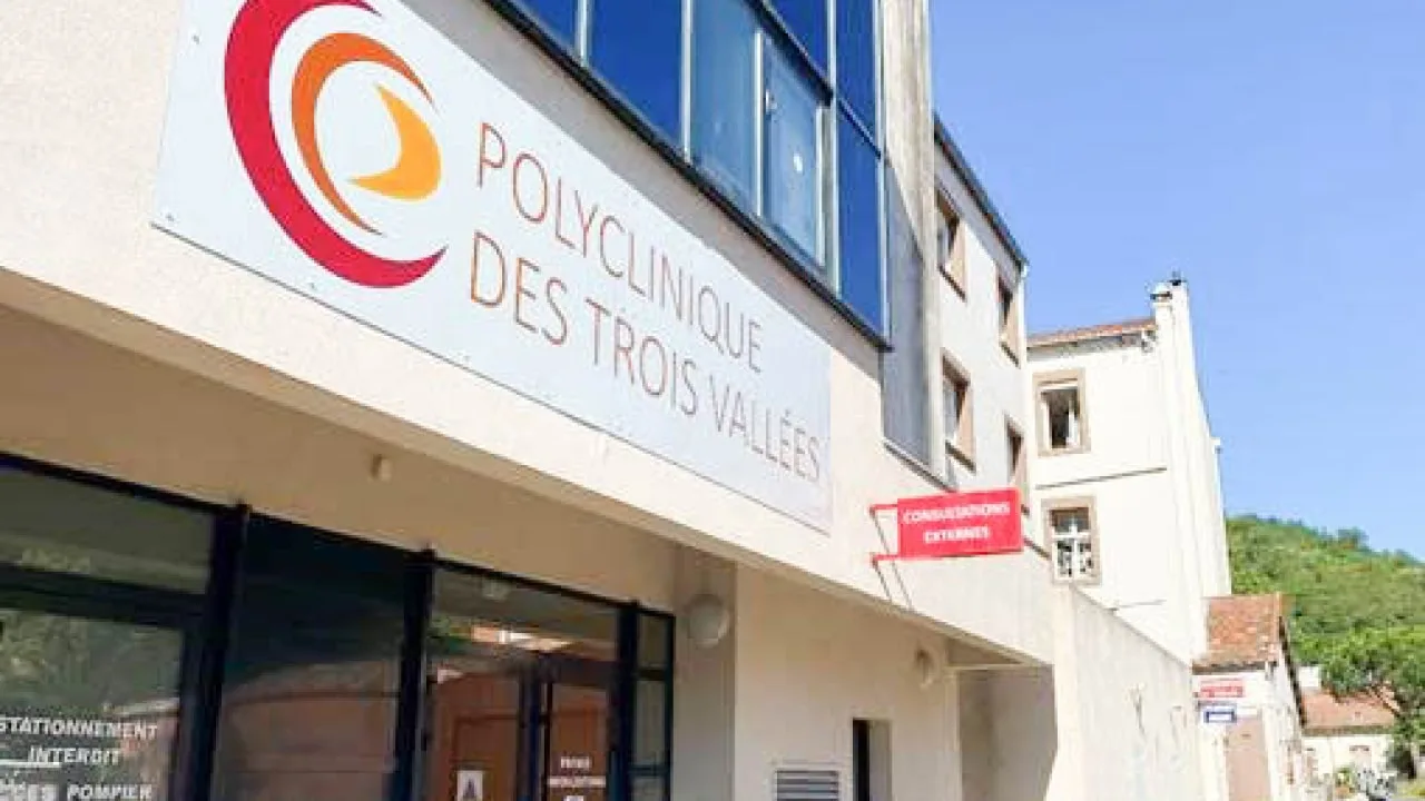 Façade blanche avec un grand panneau à logo rouge et orange, et une petite enseigne rouge à l'entrée